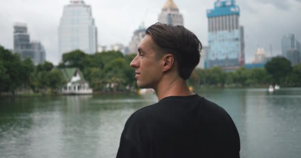 Чоловік Дивиться Озеро Громадському Міському Парку Сучасними Будівлями Хмарочосів Місті — стокове відео