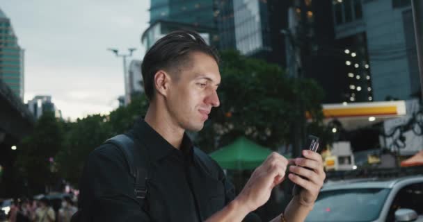 Sırt Çantalı Bir Adam Parlayan Işıklar Arasında Akıllı Telefon Kaydırıyor — Stok video
