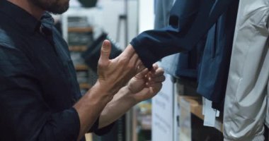 AVM 'de duran tanınmayan bir adam iş alışverişi için böyle bir takım elbise seçer. Erkek ceketin koluna dokunur ve iş için kaliteli alışverişi değerlendirir. modern moda eğilimleri