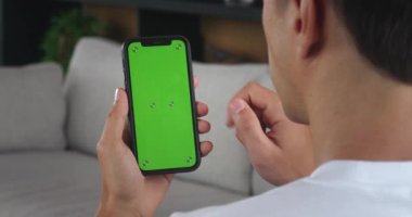 Omzundan vurulan erkek, akıllı telefonu dikey pozisyonda tutuyor. Tanımlanamayan bir adam yeşil ekrana vuruyor ve kapalı ofisteki akıllı telefonu kullanıyor. Krom tuş modelleme konsepti