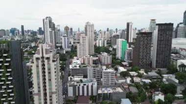 Gündüz vakti Bangkok 'taki büyük şehir binalarının üzerinde uçuyor. Modern yüksek binaları ve gökdelenleri olan büyük şehrin hava görüntüleri. Gökdelenleri ve gökdelenleri olan sinematik metropol..