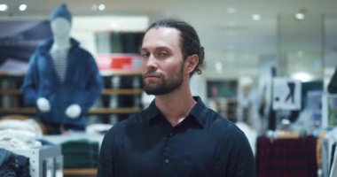 Moda mağazasının erkek portresi. Sakallı, stil sahibi bir adam moda mağazasında bir giyim mağazasının arka planında duruyor. Kara Cuma indirim saati moda mağazasında.