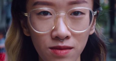 Gözlüklü genç Asyalı kadının yakın çekimi kameraya yöneltilmiştir. Bakışı zarif bir zarafetin vücut bulmuş hali. Kadın eşsiz enerjisini iletiyor. Kameraya bakan kadın hikayesini anlatıyor gibi görünüyor.