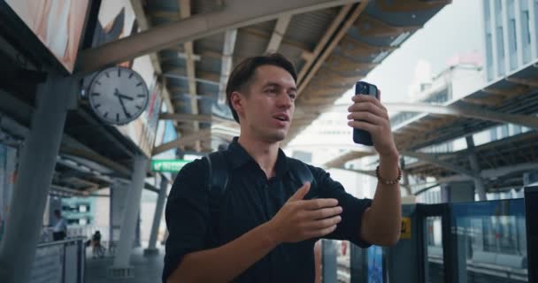 Turista Masculino Com Mochila Fazendo Videochamada Com Smartphone Enquanto Espera — Vídeo de Stock