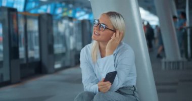 Metroda oturup müzik dinleyen bir kadın. Gürültülü metro kulaklıklarında beklemek sıkıcı metro seslerini bastırmak favori müziğin yardımıyla keyifli, mutlu duygular yaşatmak sıkıcı.