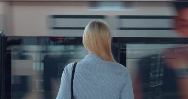 地铁里的女人从后视镜往回看金发碧眼的女商人在地铁里静静地等着火车 妇女在地铁站等着看路过的火车的后视镜 — 图库视频影像