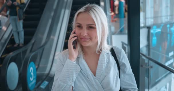 妇女在自动扶梯使用电话 年轻的千禧年女人在电话里笑着说话 美妙愉快的电话交谈与同事的朋友 女人聊天通过电话交谈 — 图库视频影像