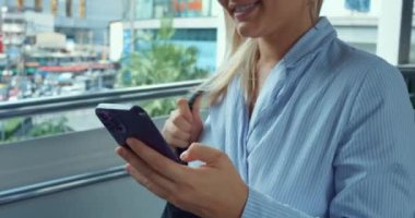 Şehirde yürüyen, telefon kullanan bir kadın. Kapatın, kadınların elleri akıllı telefonu tutuyor, mesajlar yazıyor, online uygulamaları, haberleri, web sayfalarını karıştırıyor. İş kadını iş sorunlarını akıllı telefon kullanarak çözüyor.