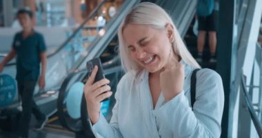 Yürüyen merdivende telefonu kullanan bir kadın. Mutlu, pozitif kadının zaferi kutlarken gülmesine şaşırdım. Tarif edilemez bir mutluluk. Neşeli olumlu duyguların dışa vurumu.