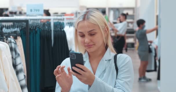 Femme Utilisant Smartphone Dans Magasin Vêtements Jeune Femme Caucasienne Joyeuse — Video