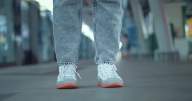 Ayaklar spor ayakkabılarda metro platformunda duruyor. Tanınmayan insan bacakları gri kot pantolonlar beyaz spor ayakkabılar. Metro metro istasyonunda tren bekliyor. Sabırsız bir şekilde toplu taşıma kavramını bekliyor