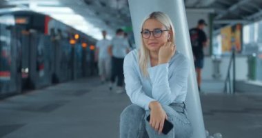 Metroda oturup müzik dinleyen bir kadın. Kafkasyalı bir kadın en sevdiği müziği kablosuz kulaklıklarla, gürültülü metroda oturup metro trenini bekleyerek ve kulaklıkla en sevdiği müziği dinleyerek sever.
