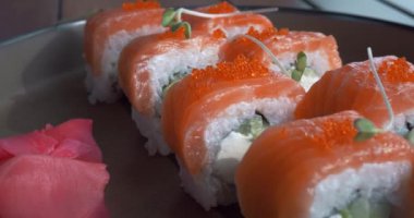 Suşi barında lezzetli Japon suşi rulolarını tabağa koy. Somon, pirinç, karides ve havyardan suşi. Geleneksel deniz ürünleri mutfağı.