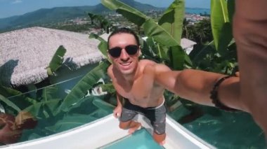 Selfie videocusu yaz tatilinde havuza atlarken kendini kameraya çekiyor. Gözlüklü aktif bir adam havuza atlar ve yaz tatilinde suya dalarken kendini filme alır..