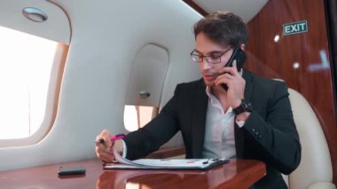 Siyah takım elbiseli beyaz gömlekli bir adam, telefon kulübesinde telefon konuşmaları yapıyor. Telefon konuşmaları ciddiyetini gösteriyor. İş ve önemli telefon konuşmaları için rahat uçuş ayarları