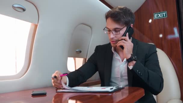 黒いスーツの白いシャツの男は 飛行機のキャビン電話の会話で電話の会話を示しています深刻さを 仕事と重要な電話会話のための快適なフライト設定 — ストック動画