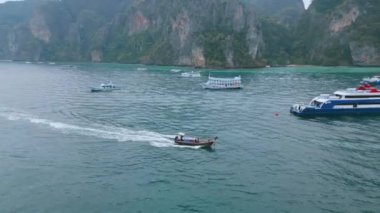 Tekne okyanusta, denizde. Gondol kayığı okyanus suyunun yüzeyinde hareket eder ve arkasında iz bırakır. Turizm, seyahat, tatil köylerindeki eğlence. Krabi, Tayland, 23 Aralık 2023