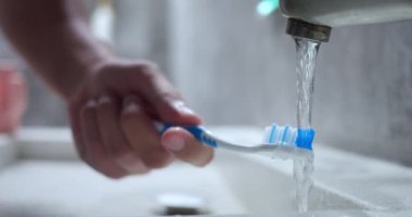 Suyun altında el temizleme diş fırçası. İnsan, daha rahat fırçalama süreci için kılları yumuşatmak amacıyla akan suyun altında diş fırçası kıllarını ıslatır. Yaklaş, Ağır Çekim. Diş fırçalama konsepti.