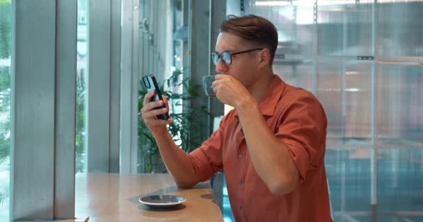Hombre Sienta Mesa Sorbiendo Café Navegación Smartphone Estilo Vida Urbano — Vídeos de Stock