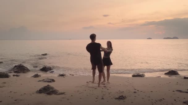 Ζευγάρι Περιστρέφεται Χέρι Χέρι Στην Παραλία Ηλιοβασίλεμα Χύτευση Πορτοκαλί Λάμψη — Αρχείο Βίντεο