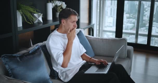 Mannen Sitter Soffan Vardagsrummet Och Koncentrerar Sig Sin Laptop Millennial — Stockvideo