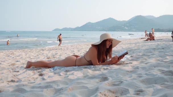 躺在海滩上的女人喜欢平静的大海 而读书则拥抱了读书的简单乐趣 当她看书时 她发现大海的节奏是平静的 文学的欢乐是永恒的 — 图库视频影像