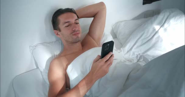 Ξύπνιος Άνθρωπος Ξαπλωμένος Στο Κρεβάτι Χρησιμοποιώντας Παράθυρο Του Τηλεφώνου Κόσμους — Αρχείο Βίντεο