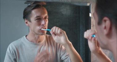 Adam banyoda dişlerini dikkatlice fırçalıyor ama sorunu var. Aşırı hassas diş etlerinden dolayı acı çeken bir adam sorunu. Bu yaygın sorun erkekleri günlük ağız temizliği rutinlerinde rahatsız eder.