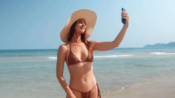Женщина Бикини Шляпе Делает Селфи Пляже Наслаждаясь Моментом Делая Селфи — стоковое видео