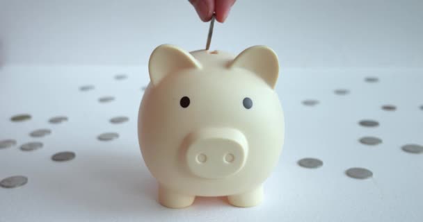 Tangan Hati Hati Menempatkan Koin Dalam Piggy Bank Meja Putih — Stok Video