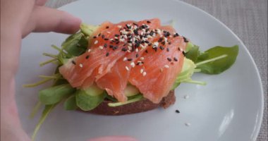 Kırmızı balık, susam, avokado ve sağlıklı besinli sebzeli sandviç. Besin ile tadı birleştirmek, sağlıklı yiyecek seçimlerinin özü. Her ısırık sağlıklı yiyeceklere olan bağlılığını gösteriyor.