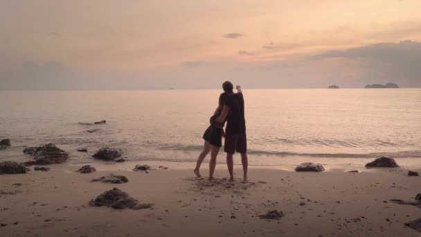 커플은 사랑을 상징하는 오렌지 해변에 일몰에 그들의 실루엣은 배경에서 따뜻함과 — 비디오