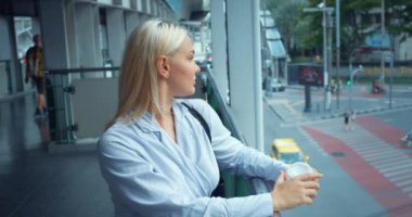 Köprüde bir fincan kahveyle bir kadın. Resmi olarak kendine güvenen iş kadını şehir merkezindeki köprüde dikilmiş kahve fincanıyla şehri yukarıdan seyrediyor. Başarı ve güven kavramı.