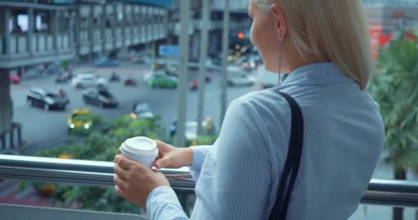 女人在城市桥上喝咖啡 回到市中心商业区的成功的年轻的高加索女人 享受着咖啡杯 欣赏繁忙的城市风景和过往的汽车 — 图库视频影像