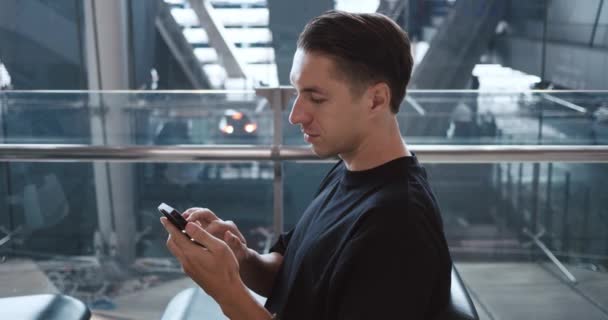 在机场候机楼候机的座位上 高加索商人乘客使用智能手机享受社交媒体的乐趣 男子在旅行时浏览智能手机 — 图库视频影像