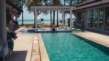 Deniz kıyısındaki lüks villada özel havuzda yüzen bir adam. Huzurlu bir havuzda yüzer. Okyanus kıyısındaki Villa 'nın dinginliğinin tadını çıkarır. Özel havuzu olan huzur sunar. Geri çekilmek için mükemmel bir rahatlama.