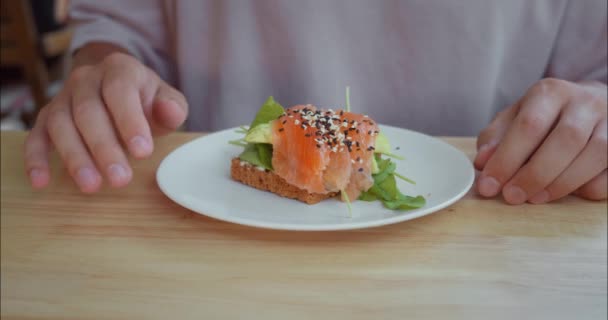 Homem Leva Delicioso Sanduíche Com Salmão Ervas Frescas Almoço Prato — Vídeo de Stock