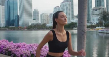 Kadın sporcu, şehir parkının göl kenarındaki patikalarında zarif bir şekilde koşuyor. Kadın spor yapıyor aktif yaşam tarzı koşuyor yaz şehri hava durumu spor yapıyor aktif yaşam tarzı sağlık kadını