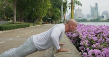 Şehir parkında şınav çeken yaşlı bir adam halk parkında sağlıklı bir yaşam tarzında şınav çekiyor. Şehir parkında spor yapan adam şehrin sokaklarında şınav çekiyor.