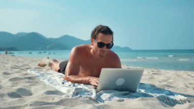 Serbest çalışan profesyonel olarak kumsalda dizüstü bilgisayar kullanıyor. Çevredeki güzelliğe ve baştan çıkarıcı plaja rağmen erkek işi. Deniz melteminden esinlenerek serbest çalışanlar, eğlence ile birlikte sıkı çalışırlar.