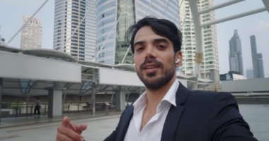 Kurumsal kıyafet videosundaki kişi el sallayan kameralara bakıyor. İş ortamında resmi giyinmiş bir adam video çağrısına bağlanır ve kameraya hoş geldin görüntüsü verir.