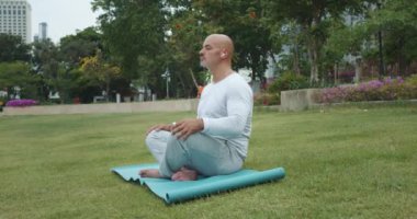 Lotus pozisyonundaki adam parkta meditasyon minderi. Meditasyona odaklanmak sakin nefes almak ve doğanın koşuşturma ve koşuşturmadan kaçmak için çıkardığı seslere. Meditasyon stresi azaltmak için etkili bir yoldur.