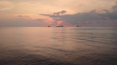 İnsansız hava araçları dingin deniz boyunca dağlara karşı canlı turuncu günbatımına doğru uçar ve dinlenir. Bu barışçıl yolculuk dinlenmeyi sembolize ediyor, doğada dinlenmenin özünü yansıtıyor.