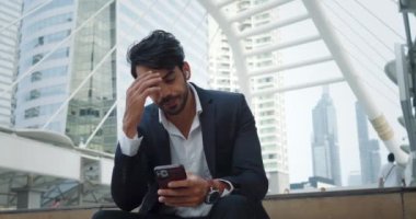 Yüzü asık bir iş adamı finans bölgesinde oturan ekran telefonuna bakar. Başarısızlıkla ilgili hayal kırıklığı verileri insanı üzer. Kambur sırt ve sarkık omuzlar derin üzüntüleri gösterir.