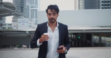 Aktif iş adamı işe giderken telefonda bir fincan kahve yazma mesajıyla yürüyor. Kahveni yudumladıktan sonra yazmaya devam et. İşkolik için kahve ve cep telefonu esasları