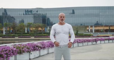 Spor giyim sektöründe güçlü bir atletizm ustası şehir seti önünde kollarını kavuşturmuş duruyor. Güçlü vücut, dayanıklılık ve irade gerektiren sıkı eğitimin sonucudur. Güçlü karakter hedeflere ulaşmada yardımcı olur