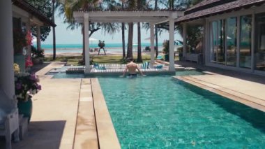 Görkemli okyanus adamı özel villa havuzunda yüzmeyi seviyor. Tropiklerin ortasında havuzu olan lüks bir villa. Rahatlamak ve dinlenmek için mükemmel. Özel havuzdaki berrak sularda yüzen bir adam.