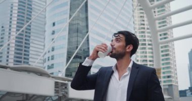 Ofis çalışanı molada dışarıda duruyor, kahve fincanı içiyor. Adam ara verip işi aceleye getiriyor sıcak içkinin tadını çıkarıyor ve telefonda mesaj yazıyor. İşçi açık havada kısa moladan hoşlanıyor