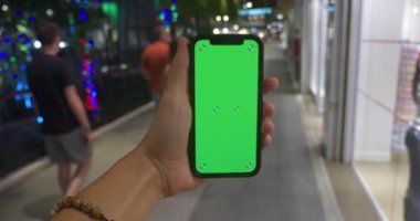 Adam fotokopi için yeşil ekranı kullanıyor. Chroma tuşu elinde akıllı telefondan model alınıyor. Adam cep telefonu kullanıyor, yeşil ekran kullanıyor ve şehrin ön tarafında duran fotoğraf veya resimleri araklıyor
