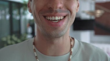 Genç adam kameraya sıcak bir şekilde gülümsüyor gerçek mutluluk canlandırıcı ruh gençlik pozitifliğini tanımlıyor. Kafkas milenyum insanı neşe içinde gülümsüyor duygusal olarak yüksek ve bulaşıcı pozitiflik